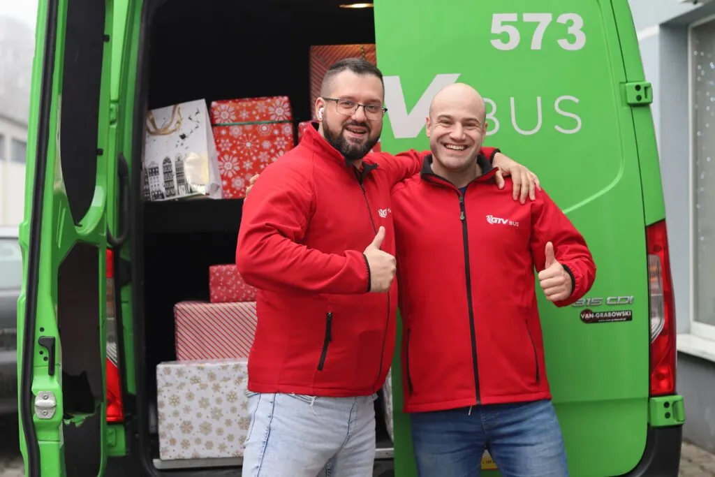 Pracownicy na tle busa z prezentami